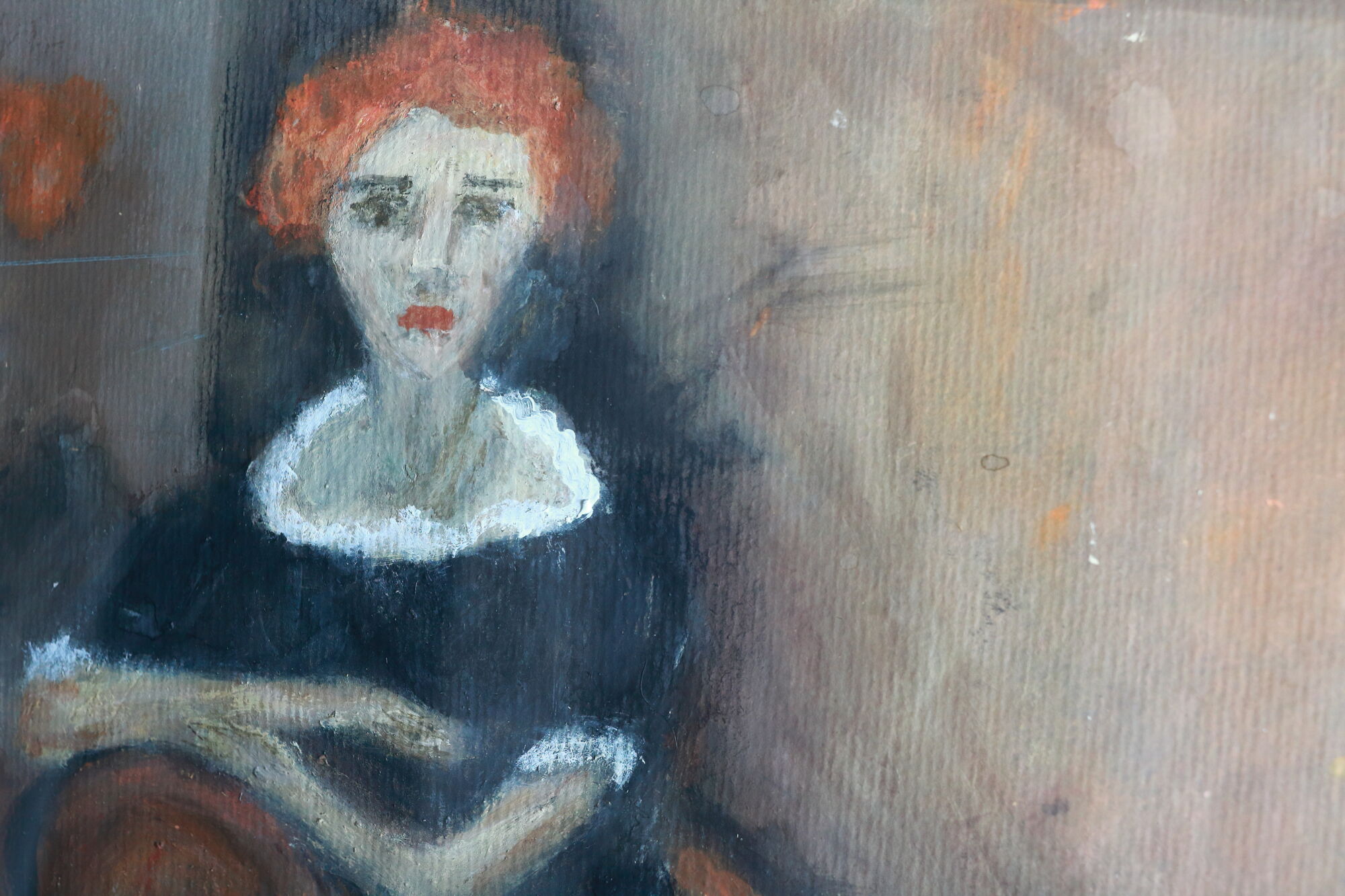 Close-up de retrato de uma mulher de cabelos ruivos curtos, vestindo vestido preto com gola branca, mãos repousadas e fundo neutro.